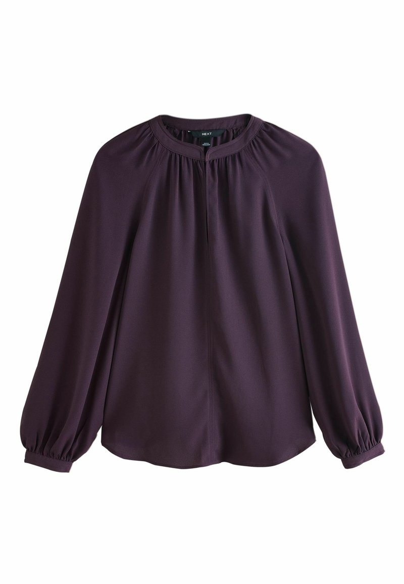 Blouse à manches longues violet foncé avec col rond, détails froncés au col et aux poignets, et finition en tissu fluide et lisse.