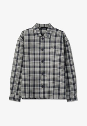 Cămașă în carouri negre și gri, cu nasturi, guler, mâneci lungi și un mic logo alb pe pieptul stâng.