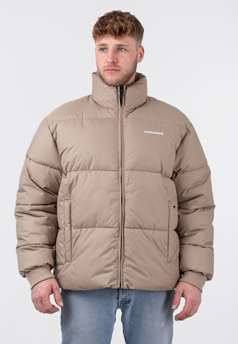 Beige gepolsterte Jacke mit hohem Kragen, Reißverschluss und Seitentaschen. Verfügt über gerippte Bündchen und ein geprägtes Logo auf der Brust. Lässige Passform.