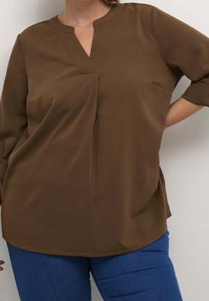 Blouse légère marron avec un décolleté en V, des manches trois-quarts et une petite poche poitrine. Texture lisse avec une coupe décontractée.