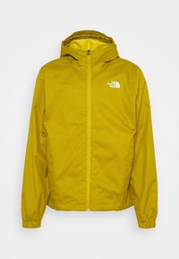 Chaqueta impermeable amarilla con capucha, puños elásticos y cierre de cremallera. Presenta un pequeño logo blanco en la parte superior izquierda.