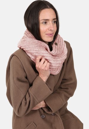 Chunky lyserød strikket infinity-scarf båret over en brun frakke, med et tekstureret mønster og en knapdetalje til sikker lukning.