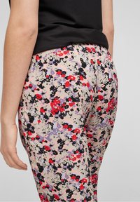 Leggings floraux dans un mélange de couleurs pastel avec des fleurs rouges, noires et violettes. Tissu doux avec une taille élastique.