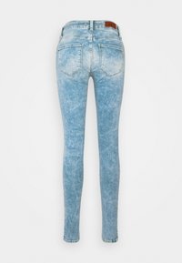 Jeans ajustados de denim azul claro con un lavado desvanecido, que cuentan con dos bolsillos traseros y una cinturilla de altura media. Etiqueta de marca de cuero en la parte posterior.