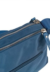 Bolsa de nylon azul con múltiples compartimentos con cremallera, equipada con herrajes plateados, superficie texturizada y una correa desmontable.