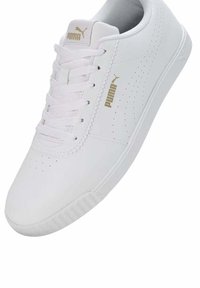 Białe sportowe buty z gładkiej skórzanej cholewki, perforowanymi detalami po bokach, białymi sznurówkami oraz złotym akcentem logo na boku i języku.