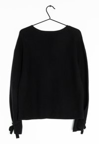 Schwarzer Langarmpullover mit Bootsausschnitt, der an einem schwarzen Drahtkleiderbügel hängt und geknotete Bündchen hat, auf einem weißen Hintergrund.