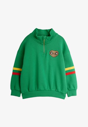 Zelený pulóver so zvýšeným golierom, ktorý má zips na prednej strane a výšivku tváre mimozemšťana. Prúžky v červených a žltých akcentoch.