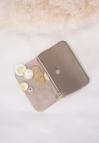 Braune Lederbörse mit einem Wildleder-Innenfutter, geöffnet, um verschiedene Münzen in unterschiedlichen Größen und Farben zu zeigen, mit einem Druckknopfverschluss.