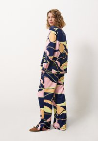 Wijduitlopende broek en een bijpassend top in navy, roze en gele abstracte patronen. Zachte stof met een relaxte pasvorm en losse mouwen.