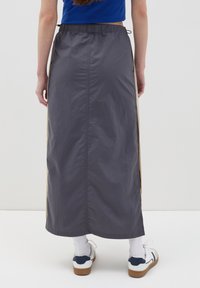 Grijze buitenrok met een trekkoord tailleband, zijsplitsen en contrasterende beige accenten. Gemaakt van lichtgewicht, textuur materiaal.