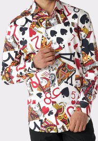Langarmshirt met een witte achtergrond, versierd met een kleurrijk speelkaartenmotief in rood, zwart en goud, met verschillende kaart symbolen en nummers.