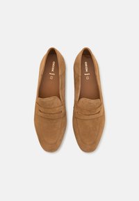 Mocasines de ante marrón sin cordones con una textura suave, que presentan una ranura decorativa para una moneda y un diseño de punta redonda. Forrados con un interior marrón.