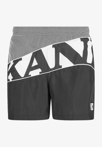 Pantalones cortos deportivos negros con una cinturilla de malla, que presentan una marca diagonal blanca. Están hechos de un material ligero, con una textura suave y detalles de costura.