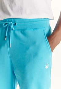 Turquoise sweatpants van een katoenmix met een elastische tailleband, een verstelbaar trekkoord en een logodetail aan de linkerkant.