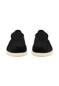 Zapatos negros de ante tipo slip-on con punta redonda, suela de goma en crema contrastante y un sutil detalle de costura a lo largo de los bordes.