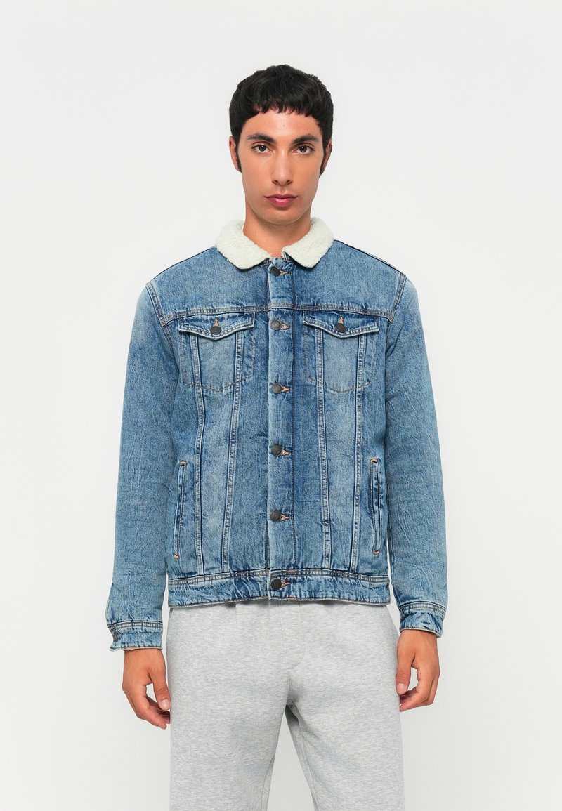 Jeansjacka i ljusblått med en imitation av fårskinnskrage. Har knappstängning, sidofickor och stickade detaljer genomgående.