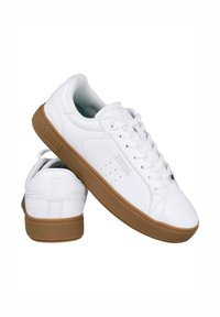 Zapatillas de cuero blancas con un diseño de caña baja, suela de goma texturizada, detalles perforados en los laterales y logotipo en la lengüeta y el talón.