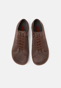 Scarpe in pelle marrone con una superficie liscia, punta rotonda e laccetti marroni; presentano un anello discreto e una fodera interna rossa con marchio.