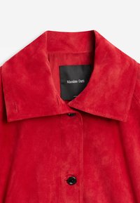 Červená semišová bunda se širokým límcem a černými knoflíky, s černou štítkem s bílým nápisem „Massimo Dutti“ uvnitř výstřihu.