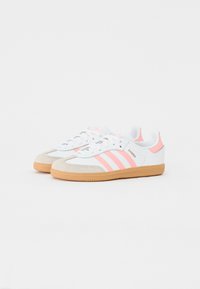 Witte sneakers met roze accenten en drie strepen, voorzien van een suède neuspunt, rubberen gumzool en een afgerond achterontwerp.