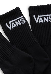 Czarne wełniane skarpetki z prążkowanymi mankietami i białym logo "VANS" po bokach. Tkanina wydaje się miękka o teksturowanym wykończeniu.