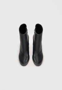 Sorte skinn ankle boots med en glatt tekstur, rund tå og en glidelås på siden for enkel tilgang. Minimalistisk design med en slank silhuett.