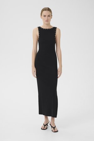 Robe noire sans manches avec une silhouette ajustée, ornée d'accents en clous argentés le long de l'encolure et d'une coupe droite jusqu'à l'ourlet.
