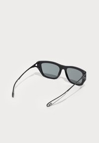 Óculos de sol retangulares pretos com lentes cinza-escuras. Feitos de plástico, com hastes elegantes e finas que apresentam um detalhe sutil do logótipo.