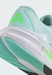 Zapatilla deportiva de color azul claro con acentos verdes, collar acolchado, parte superior texturizada y suela Cloudfoam blanca con patrones de agarre para tracción.