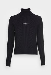 Pull à col roulé noir cannelé avec manches longues, arborant un subtil logo Calvin Klein Jeans en blanc sur la poitrine. Matière en maille douce.