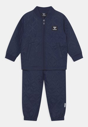 Marineblauer, gesteppter Trainingsanzug mit einer Reißverschluss-Jacke und elastischen Hosen. Merkmale sind ein Rautenmuster, gerippte Bündchen und seitliche Taschen.