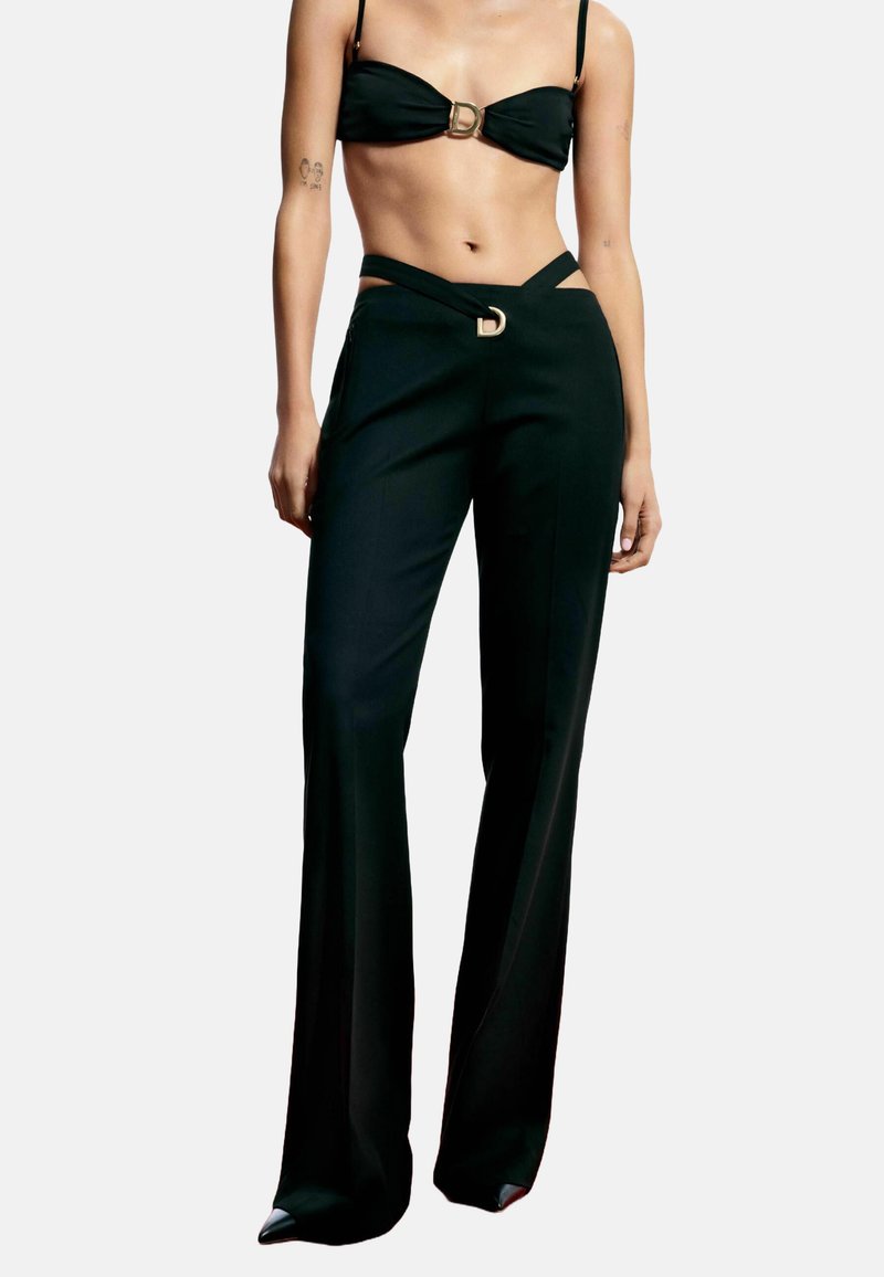 Schwarzes zweiteiliges Outfit mit einem Bandeau-Top mit goldener Schnalle und hochtaillierter Hose mit Ausschnitten und einem ähnlichen goldenen Akzent.