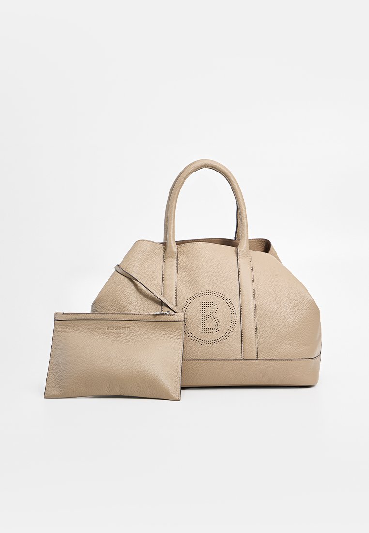 Beige lederen tote bag met een gladde textuur, ronde vorm, twee handvatten en een geperforeerd logo-detail. Inclusief een bijpassende ritszak.