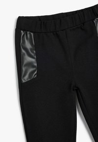 Pantalons noirs en tissu doux avec des panneaux latéraux en cuir noir. Ceinture élastique pour plus de confort, avec une texture lisse sur l'ensemble.