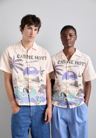 Chemises à manches courtes, de couleur pêche clair, avec des motifs tropicaux comprenant des palmiers et des tons de bleu. Conçues avec des boutons et une coupe décontractée.