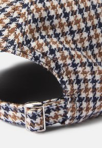 Barna, tengerészkék és fehér houndstooth mintás sapka strukturált anyagból, állítható pánttal és fémes csattal az oldalon.