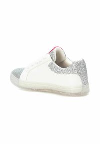 Zapatilla blanca con acentos de purpurina plateada en la punta y el talón, suela de goma texturizada y detalle rosa en la parte trasera.