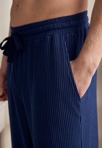 Pantaloni de loungewear bleumarin, cu textura ribbed, cu talie elastică și șnur, dotati cu buzunare laterale și o textură moale.