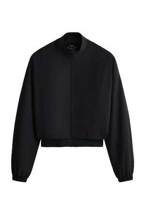 Schwarze, kurz geschnittene Jacke mit langen Ärmeln, Frontreißverschluss, Stehkragen sowie elastischen Bündchen und Saum vor weißem Hintergrund.