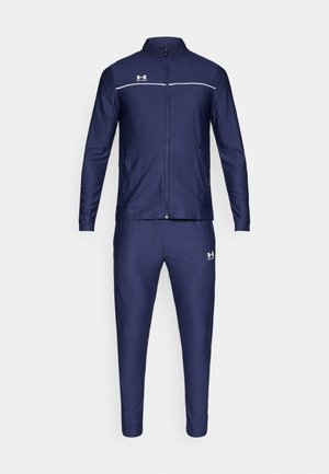 Tengerészkék melegítő szett cipzáras, álló galléros dzsekivel és hozzá illő, szűkített szárú nadrággal. Simogató tapintású anyag fehér részletekkel.