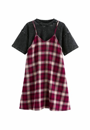 Sort oversized T-shirt over en burgunderfarvet plaid slipkjole med tynde stropper. Kjolen har hvide og grå linjer i mønsteret.