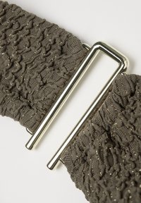 Cintura elastica in tessuto nero strutturato con macchie dorate e fibbia metallica rettangolare argentata lucida su sfondo bianco.