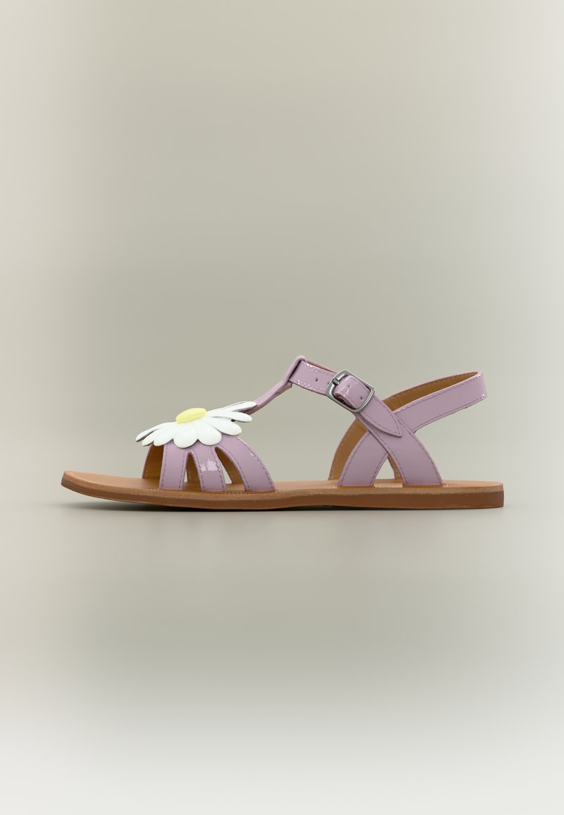 Sandale plate lilas avec bride à la cheville, fermeture à boucle, semelle marron et marguerite décorative blanche et jaune sur les lanières avant.