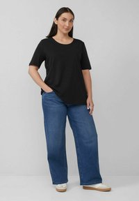 Black short-sleeve t-shirt paired with relaxed-fit blue jeans. The outfit features a classic round neckline and solid color design.
