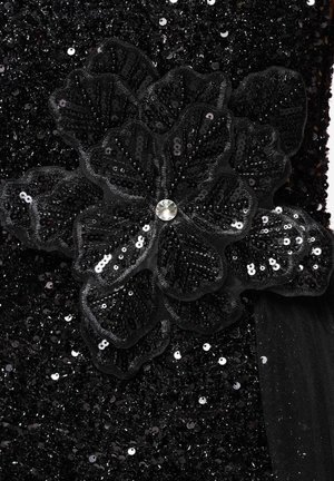 Tissu noir avec des paillettes noires densément réparties, présentant une fleur de paillettes superposées avec un strass clair au centre.