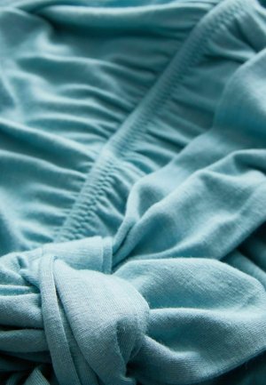 Lichtblauwe stof met een zachte, gladde textuur, voorzien van gathered details en een knoopsectie. Het materiaal lijkt lichtgewicht en rekbaar te zijn.