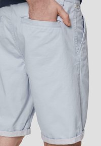 Hellblaue Shorts aus weichem Material, mit umgeschlagenem Saum, Seitentaschen und einem lockeren Schnitt, ideal für die Freizeit.