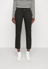 Pantalons noirs cropped en mélange de coton, dotés d'un design à cinq poches et d'un bouton à l'avant. Associés à des baskets montantes blanches.
