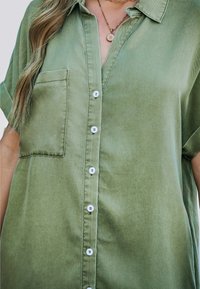 Olijfgroene, kortom mouw, knoopsluiting shirt met een borstzak, witte knopen en een gladde, gestructureerde stof.